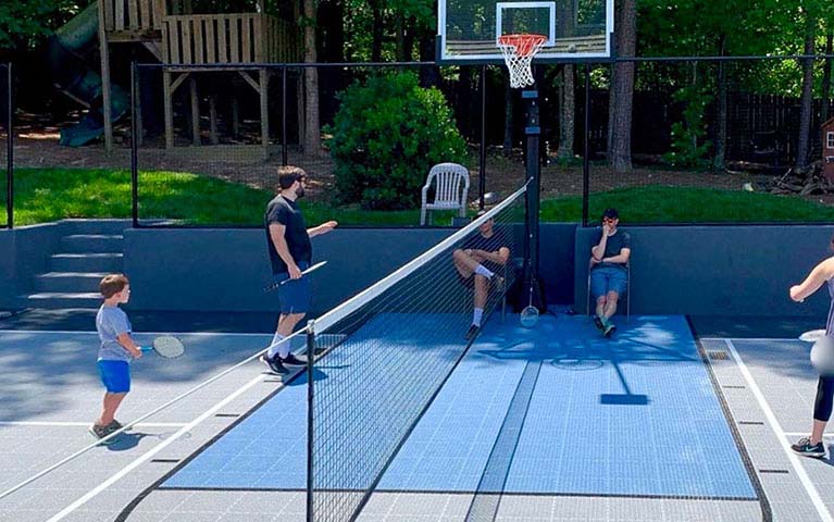 Active family playing tennis at their backyard court