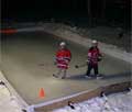 Kids playing hockey, at night, at their backyard rink built using the Rink in a Box kit