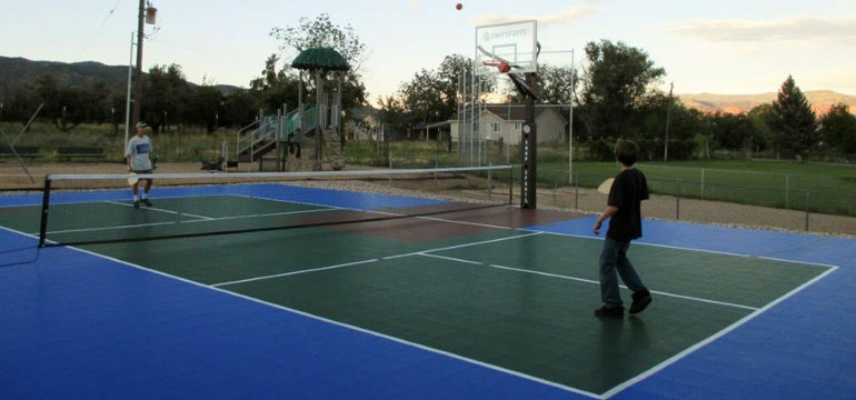 Kids practicing pickle ball at a multi game court