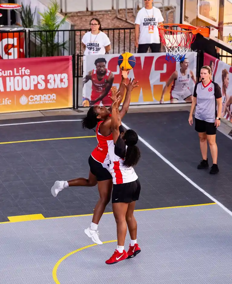 Female athletes competing on SnapSports Revolution outdoor basketball court during Sun Life Canada Hoops 3x3 National Championships with Canada Basketball branding visible