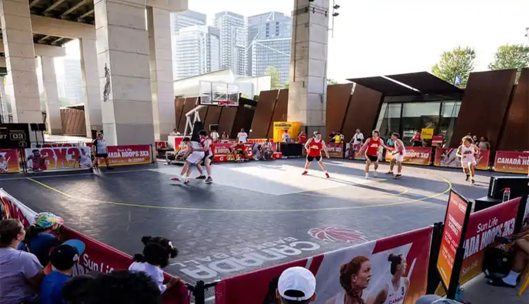 Outdoor basketball court at Sun Life Canada Hoops 3x3 National Championships at The Bentway Toronto showing SnapSports Revolution tiles with athletes competing under the Gardiner Expressway