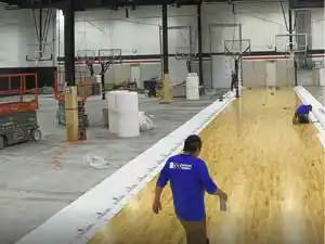 Workers rolling out underlayment and assembling Junckers Clip System hardwood basketball courts in Oakville.