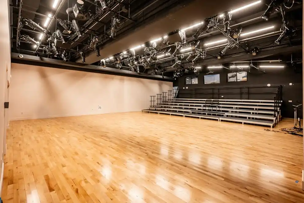 Spacious hardwood Junckers dance floor in the main theatre of the Nancy & Ed Jackman Performance Centre, with stage lighting and risers.