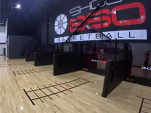 High-tech basketball shooting cages with automated ball return and digital analytics screens on Junckers hardwood.