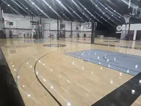 Advanced commercial basketball training courts at Shoot 360 Oakville, featuring custom grey painted keys, high-gloss Junckers hardwood flooring, and automated shooting stations.