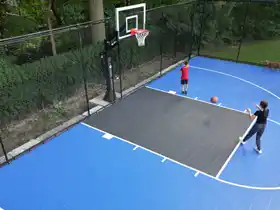 Designed for young athletes, this 23' feet by 49' feet court in North York features durable blue tiles, a professional hoop, and full containment netting.