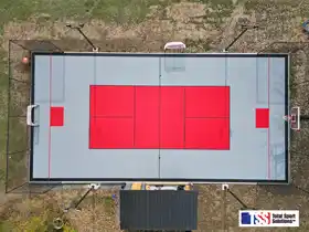 This aerial photo showcases this massive 40' by 80' Milgrove court features dual hoops, full containment, and professional lighting for hockey, pickleball, and family basketball.