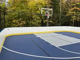 This medium 36'  x 60' multi-sport court in Parry Sound is perfect for family basketball, pickleball, volleyball, and hockey, blending luxury with its natural setting.