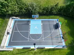 This large 40' by 60' multi-game backyard court in Nova Scotia features the iconic jumping man logo and full containment netting for safe, high-performance family play.