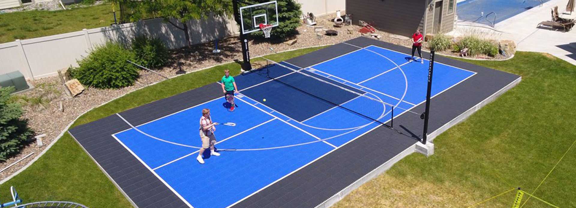 Family playing tennis in their backyard cour