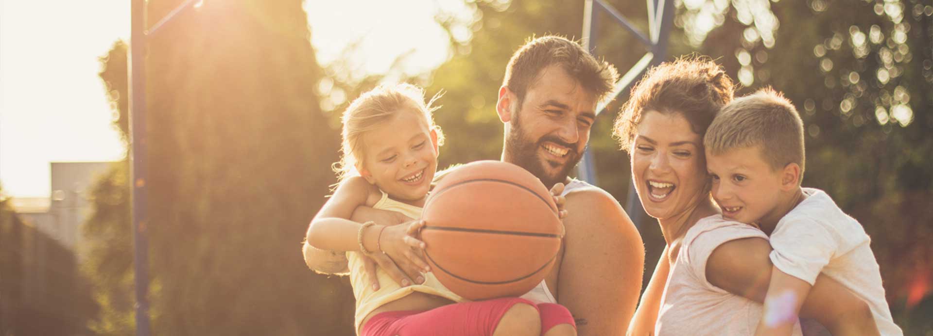 Parents and kids having a good time while playing basketball on their backyard court